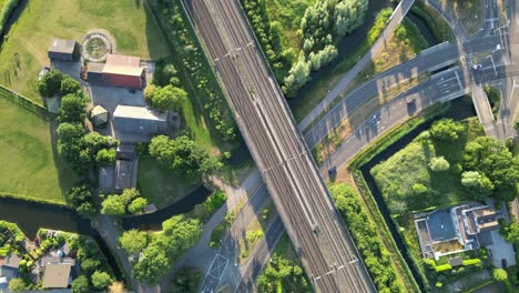 train passing by dutch city of vleuten in utrecht in a sunny weather intersecting with a street along with dutch farm