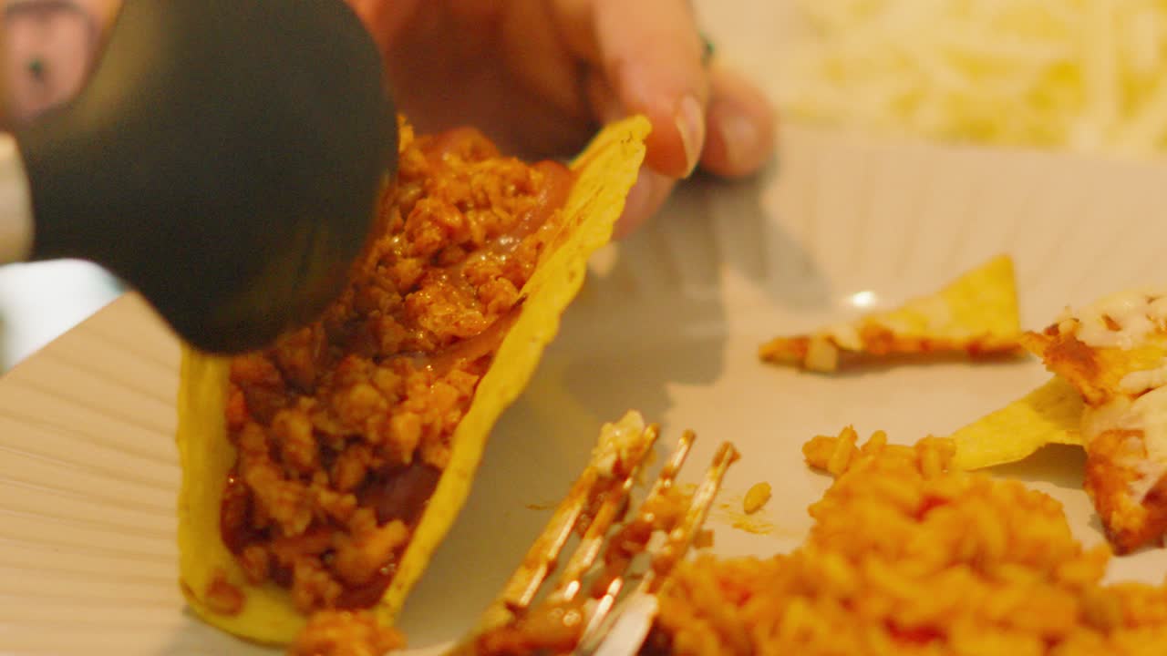 Filling Delicious Mexican Taco with Beef Mince on Plate with Rice and Nachos