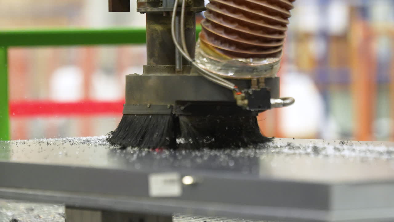 Nahaufnahme eines automatischen CNC-Fräskopfes mit Bürste und Absaugschlauch, der eine Holzplatte in einer Möbelproduktionsstätte schneidet