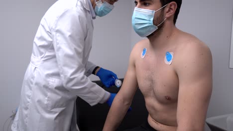 médico de cultivos aplicando electrodos de ecg en el pecho del paciente