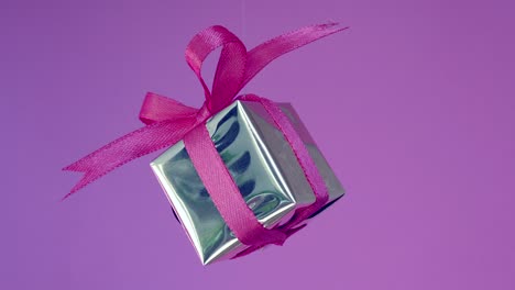 gift box with red ribbon spinning on neon purple background. 360 degree rotatio