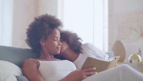 relaxed mum and daughter reading book lying in bed at daytime