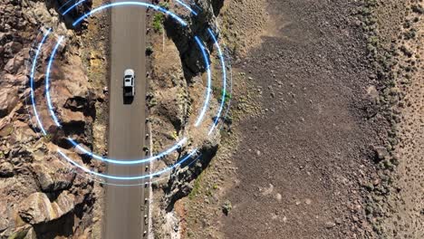 top down drone shot of a self driving car making its way through a steep desert cliff roadway