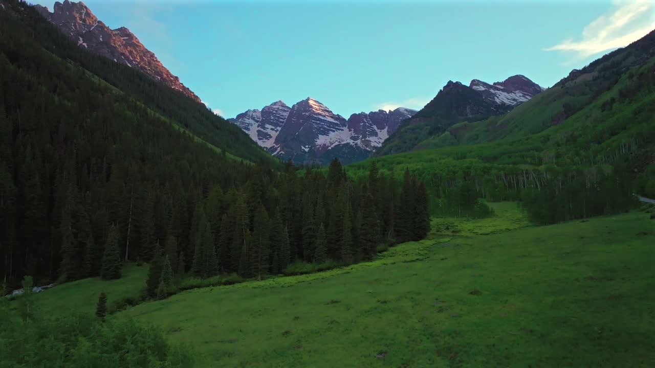 Maroon Bells Wilderness road valley Elk Range Rocky Mountains Colorado aerial drone North Maroon Pyramid Peak 14er sunset spring summer blue sky clouds Aspen Snowmass White River Forest forward pan up