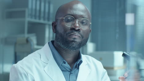 portrait of black scientist holding test tube and looking at camera in lab