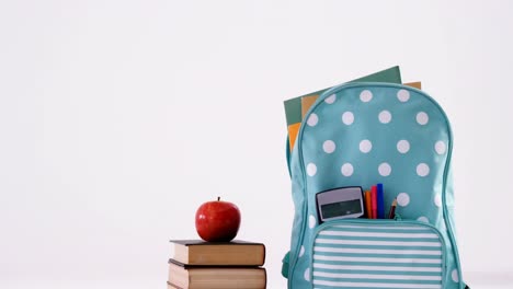 apple on book stack with schoolbag