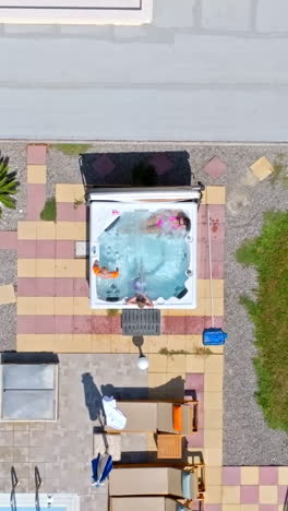 top down drone shot above a mother and kids relaxing in a jacuzzi, sunny day