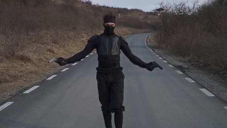 cinematic scene of a man dressed in black, partially masked and armed with two pistols, walking with a confident and intense attitude down a lonely road.