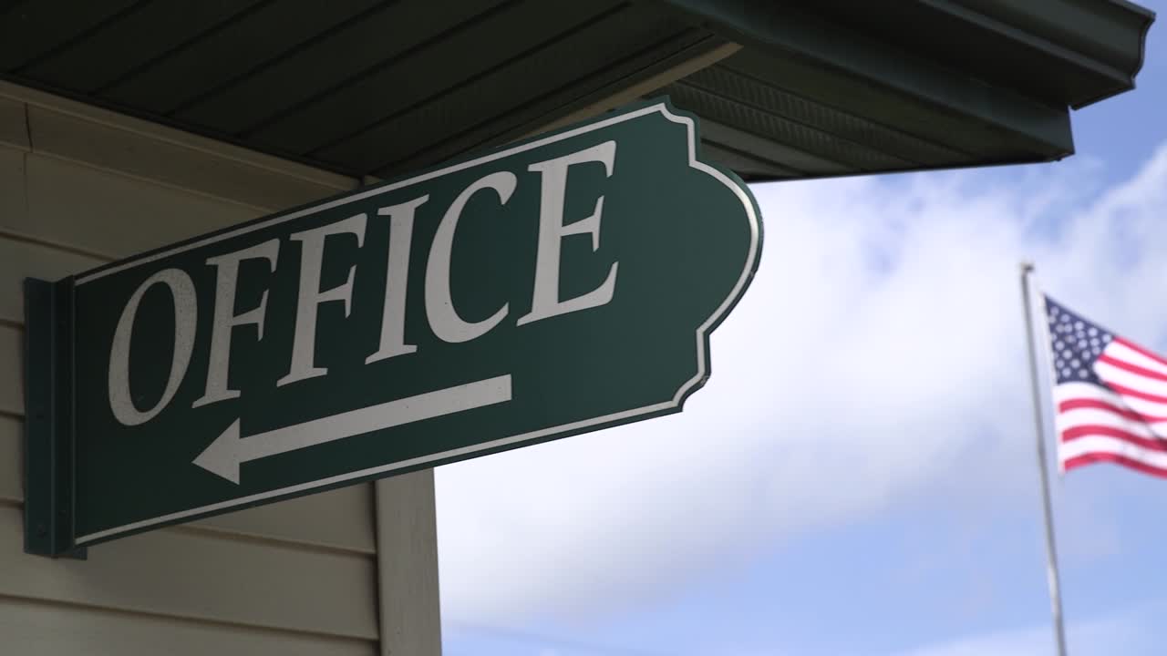 A green &amp;quot;office&amp;quot; sign with am American flag in the background