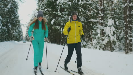 smiling man in a winter jacket skiing in the woods in slow motion with his loving wife. healthy lifestyle. young couple