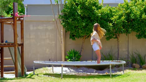 chica saltando en un trampolín en el jardín 4k