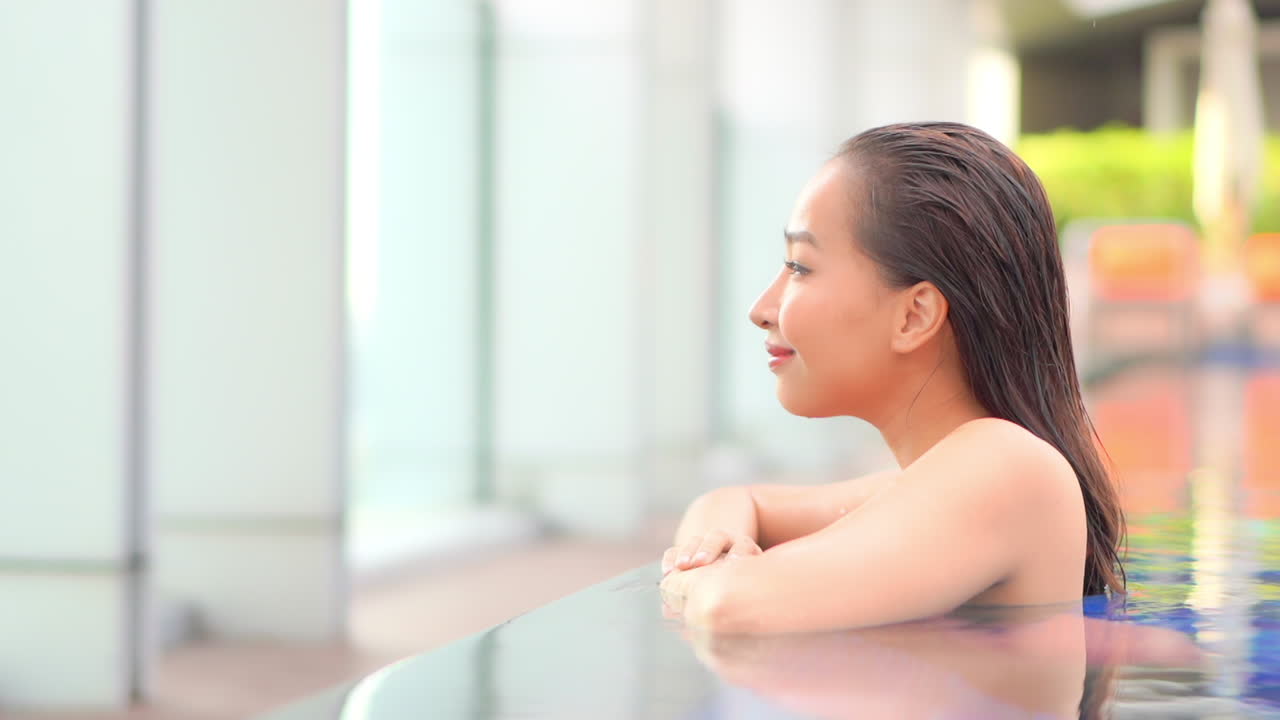 완벽한 피부를 가진 꽤 섹시한 아시아 여성은 스파 센터의 수영장에서 즐깁니다.