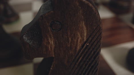 tilt down reveals wooden black knight chess piece, extreme macro closeup