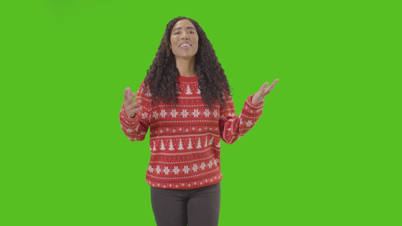 Studio Portrait Of Woman Wearing Christmas Jumper Against Green Screen Smiling At Camera Saying Merry Christmas 1