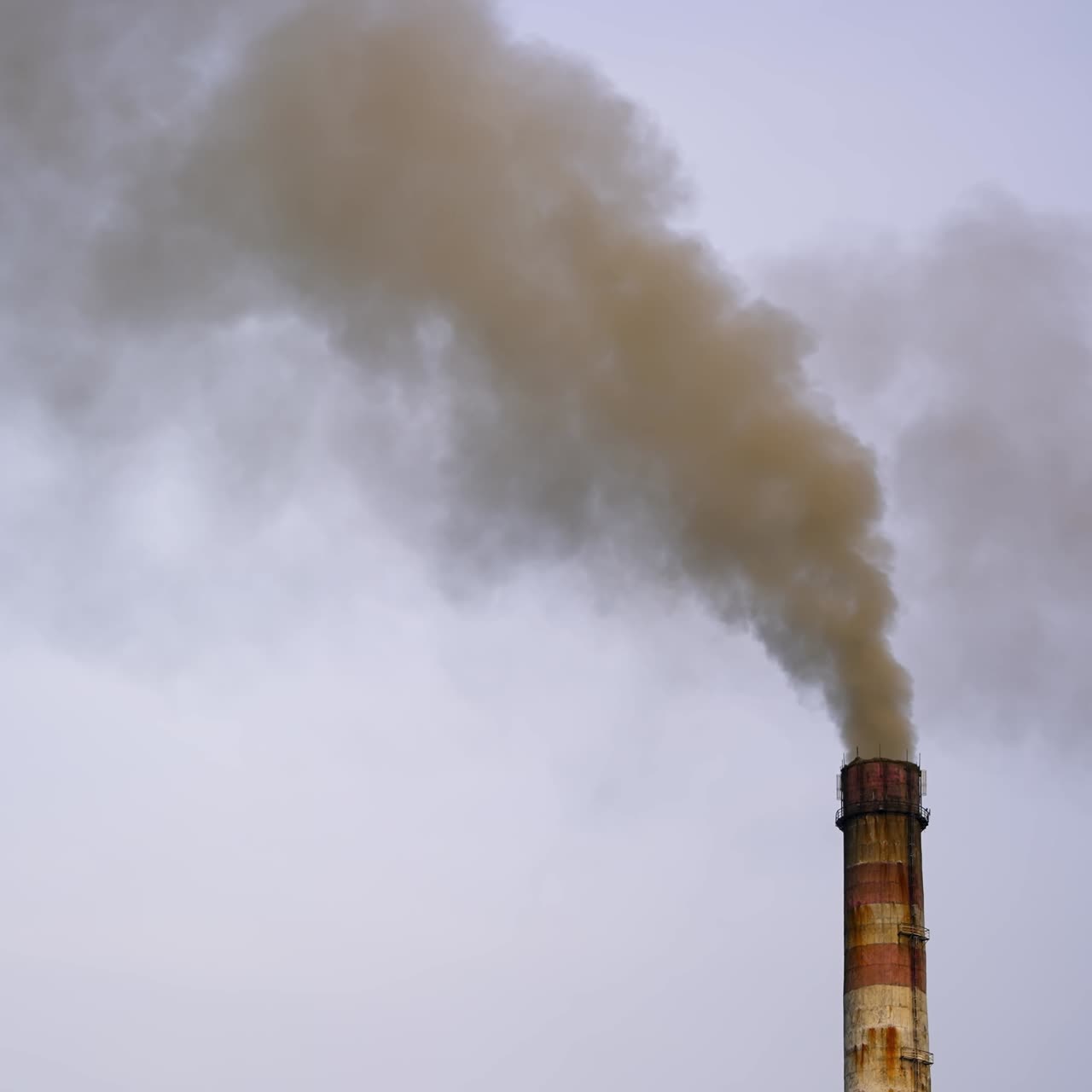 Dangerous emissions on the sky background. Dark toxic smoke clouds coming out of factory chimney. Air pollution and global warming