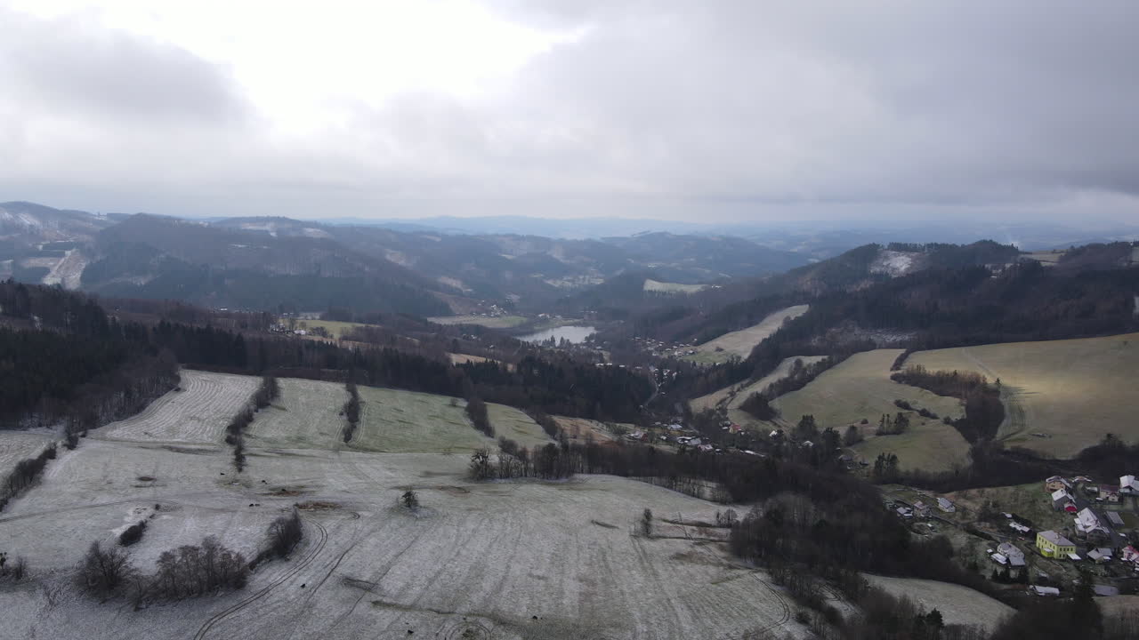 un vuelo sobre el campo con un camino que conduce a través de los árboles y una vista de los alrededores durante el comienzo de la nevada