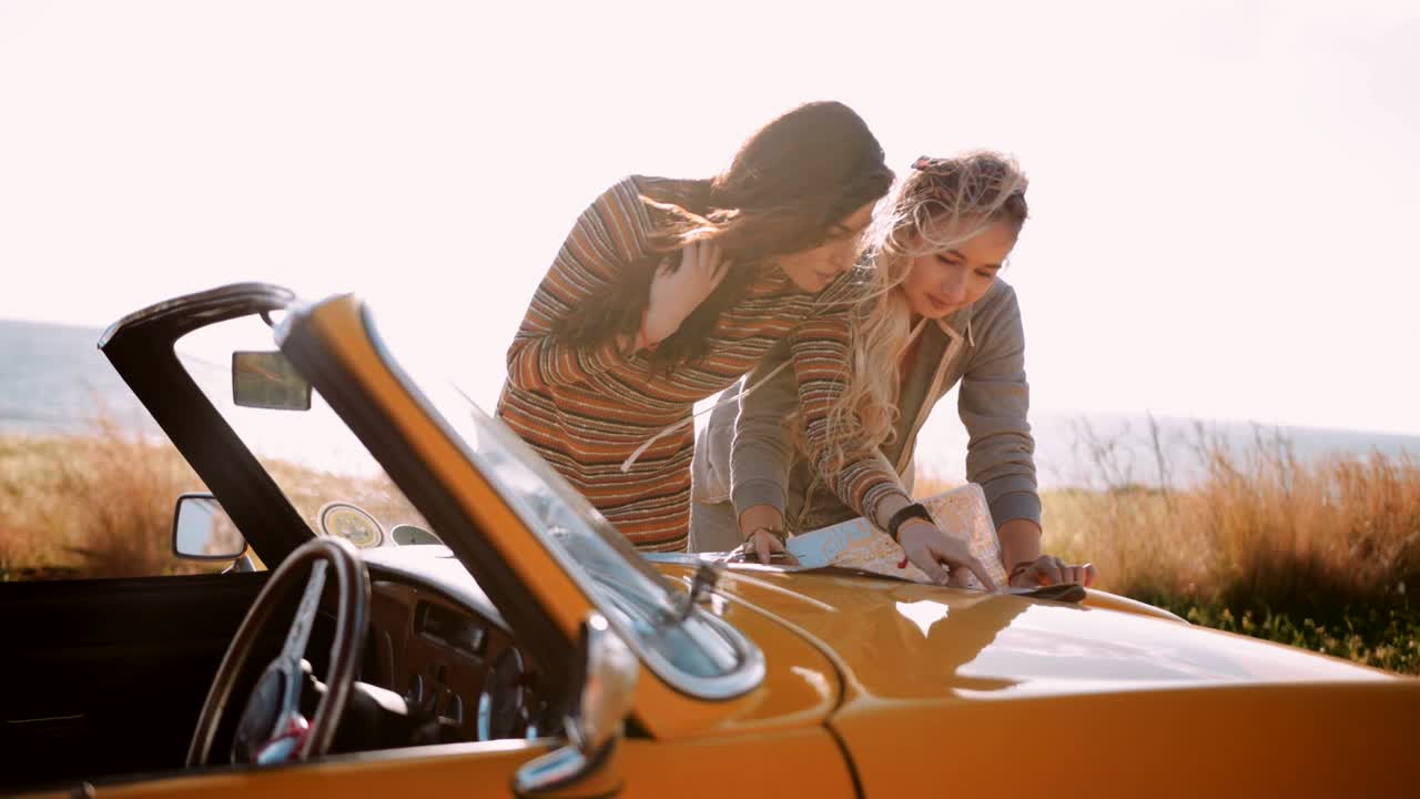 Frauen mit gelbem Retro-Cabrio und Karte an der Küste.