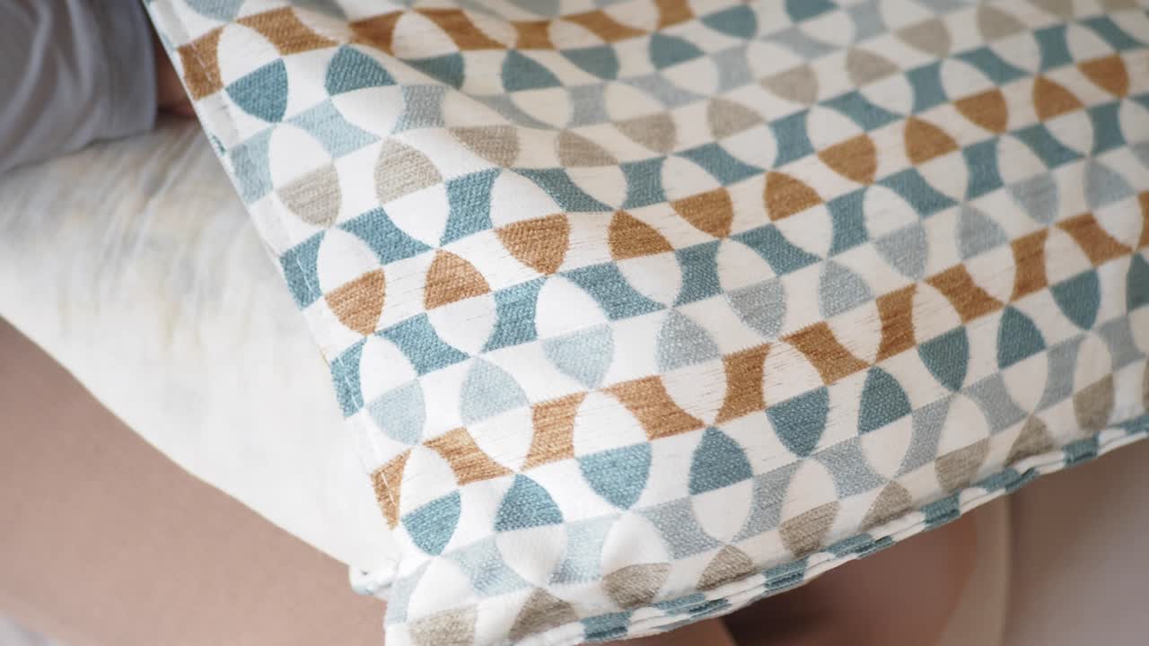 una persona que sostiene una almohada de patrón geométrico