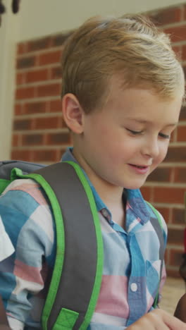 video of happy diverse boys holding books and talking in front of school