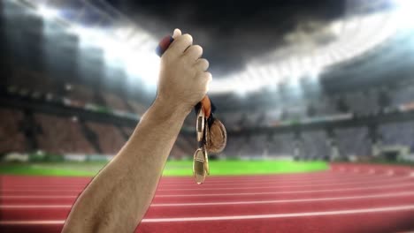 hand of athlete showing gold medals in olympic stadium