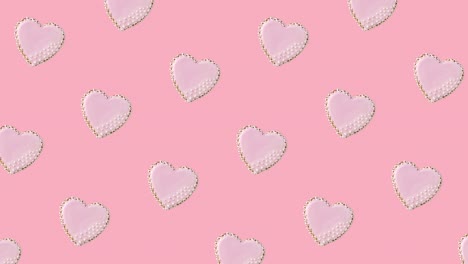 seamless looping animation with pattern of heart shaped cookies decorated by pink glaze on a pastel background, diagonal movement