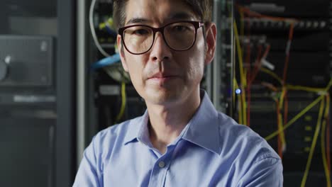 portrait of smiling asian male it technician by computer server