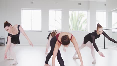 caucasian ballet female dancers exercising with a barre by a mirror during a ballet class