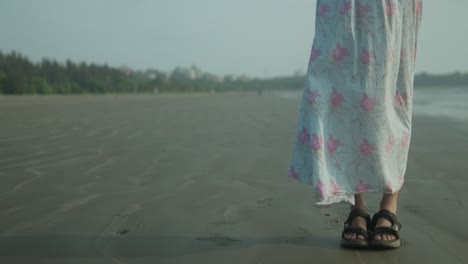 인도 의 한 여인 의 다리 는 인도 에서 꽃 의 드레스 를 입고 해변 에 서 있다
