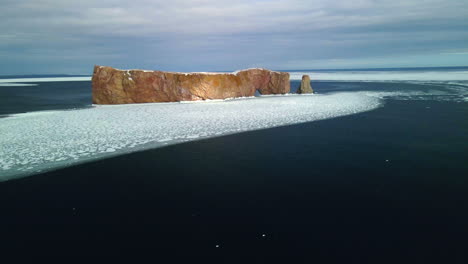 aerial view of percé rock in the winter with ice on the ocean