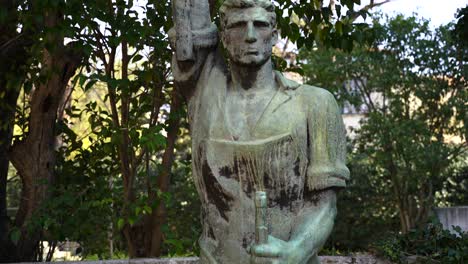 socialist realism statue of worker holding rifle and pickax on hands