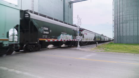 freight train transit through rural agricultural landscape and grain silos