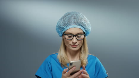 attractive young female medic in blue costume, hat and glasses speaking cheerfully on the phone and smiling