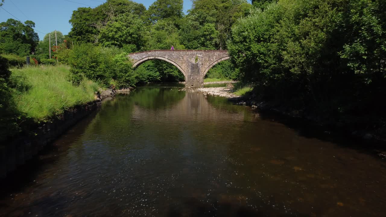 낮에는 이중 아치 다리에 서 있는 남자의 드론 영상이 상승하고 있습니다.