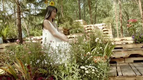 a beautiful asian woman in a flowing white gown looks out over an idyllic flower garden