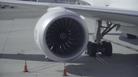 Primer-Plano-De-La-Turbina-Del-Avión-Girando-Mientras-El-Avión-Está-Estacionado-En-La-Terminal