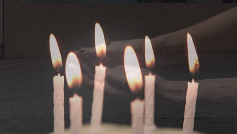 Composite video of candles blowing off over woman hands with rosary praying against people walking