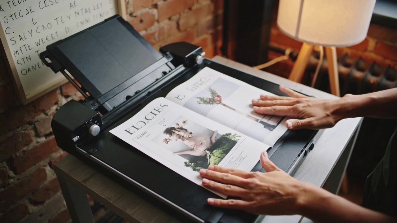 Scanner lid lifting, woman in green top placing, smoothing magazine on scanner in studio to scan