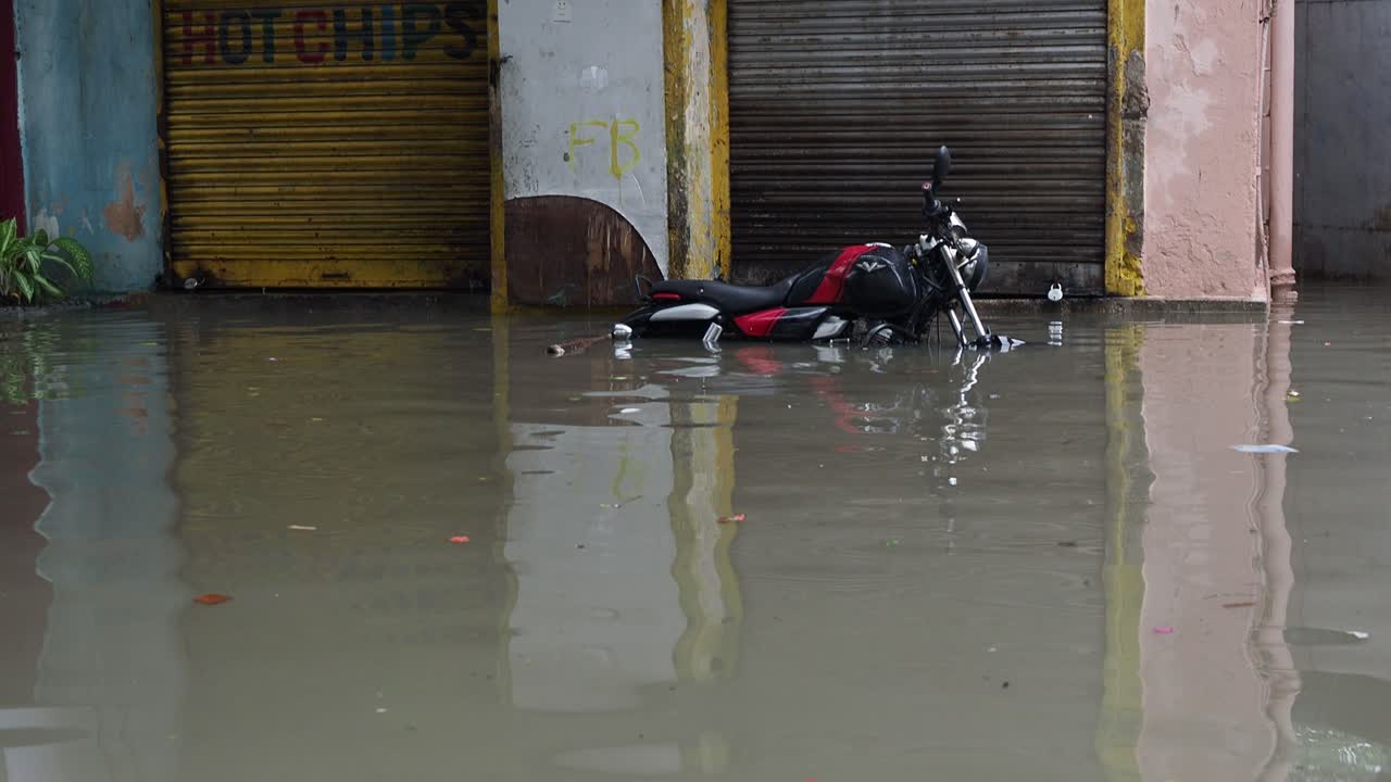Abandoned motor bike Vikrant v15 lies in water logged street. horizontal image of a broken black bike stuck in a pool of water. flooded road. flood. the river overflowed