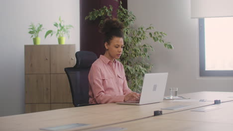 happy pregnant woman caressing her belly while working in the office