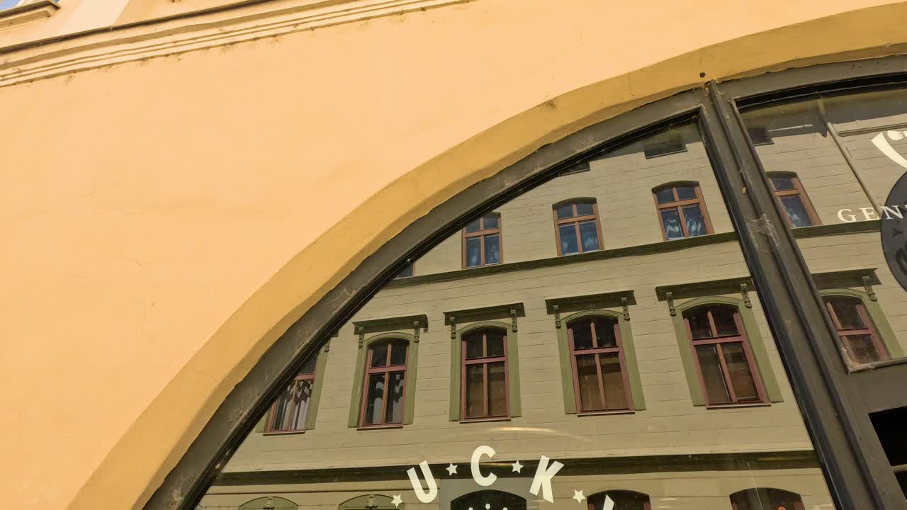Camera tilts upward, revealing round barber shop sign and historic architecture in bright daylight