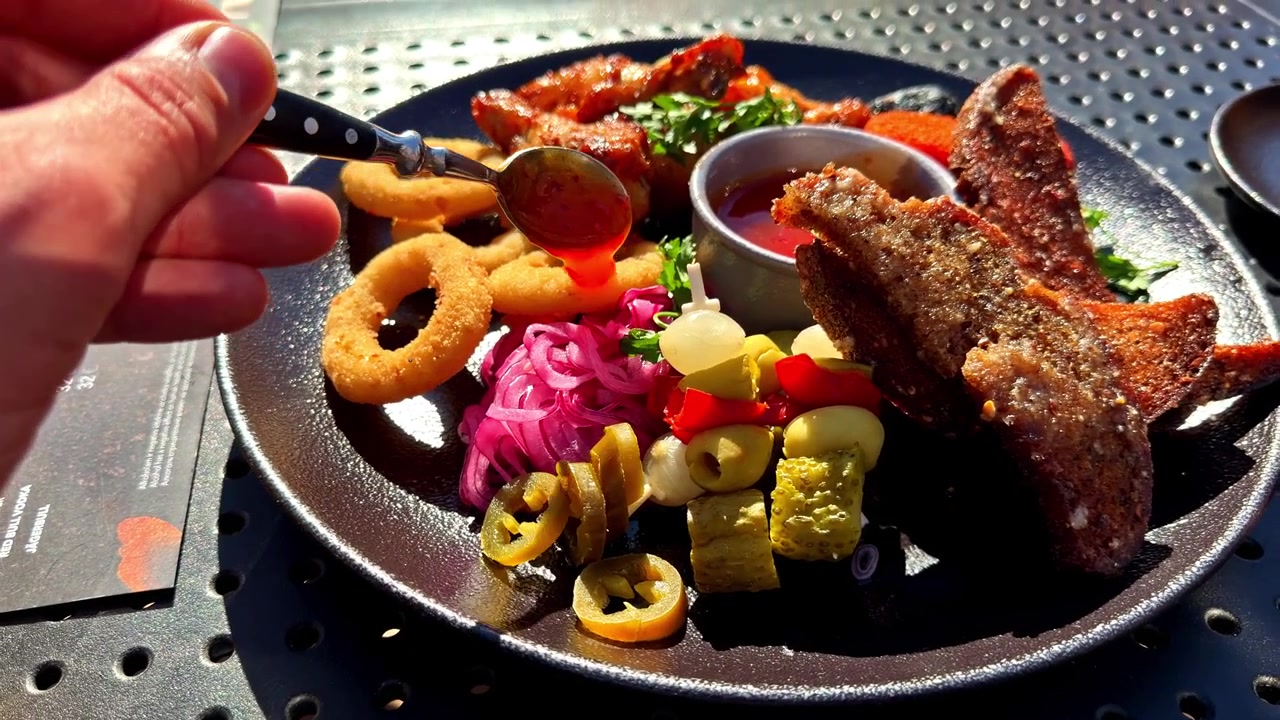 Nahaufnahme eines Tellers mit gegrilltem Fisch und Meeresfrüchten, garniert mit süßer Chilisauce.