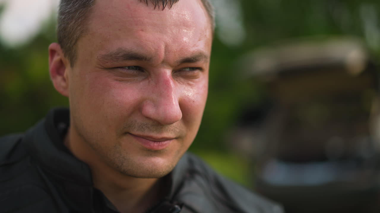 мужчина среднего возраста в черной кожаный куртке смотрит в сторону на улице