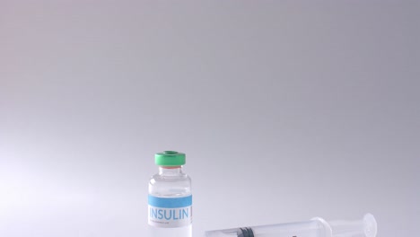 close up of insulin vial and syringe on grey background with copy space, slow motion