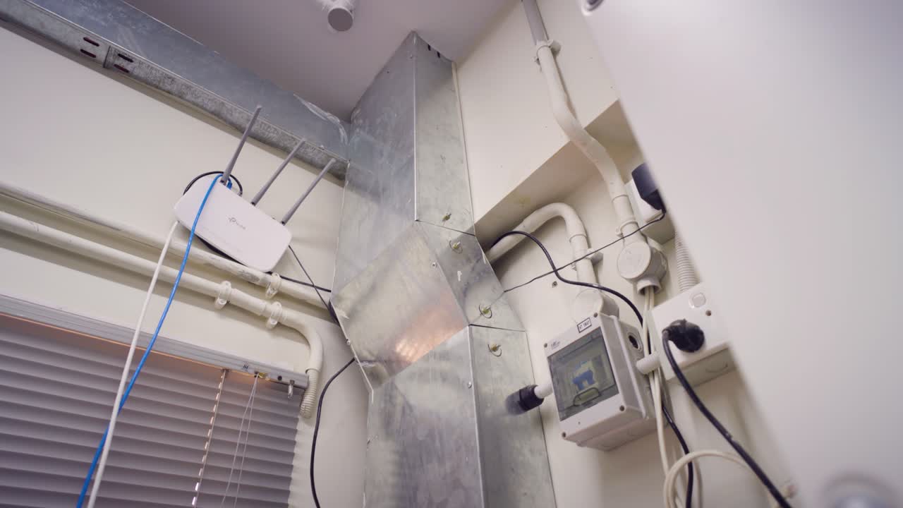 Factory wall featuring a TP Link Wi Fi router, ventilation duct, and various electrical outlets