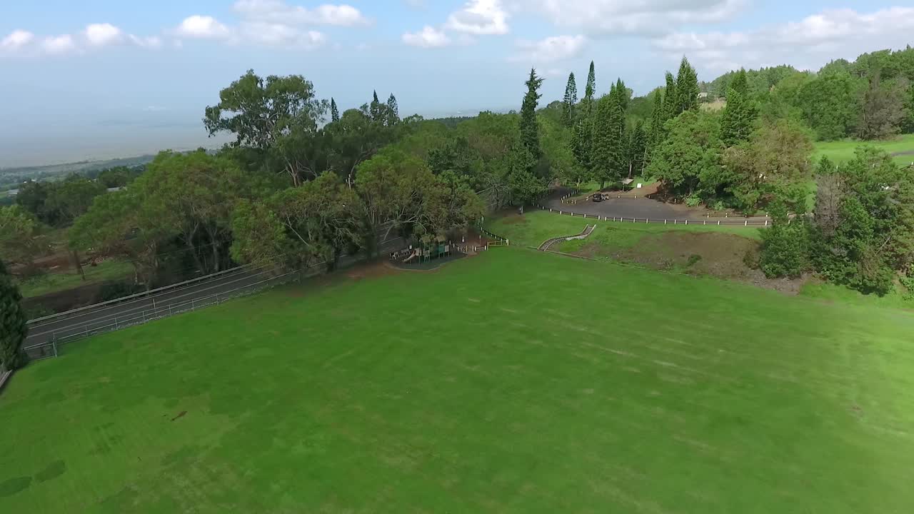 Beautiful tranquil view of Maui landscape with white clouds over green fields.