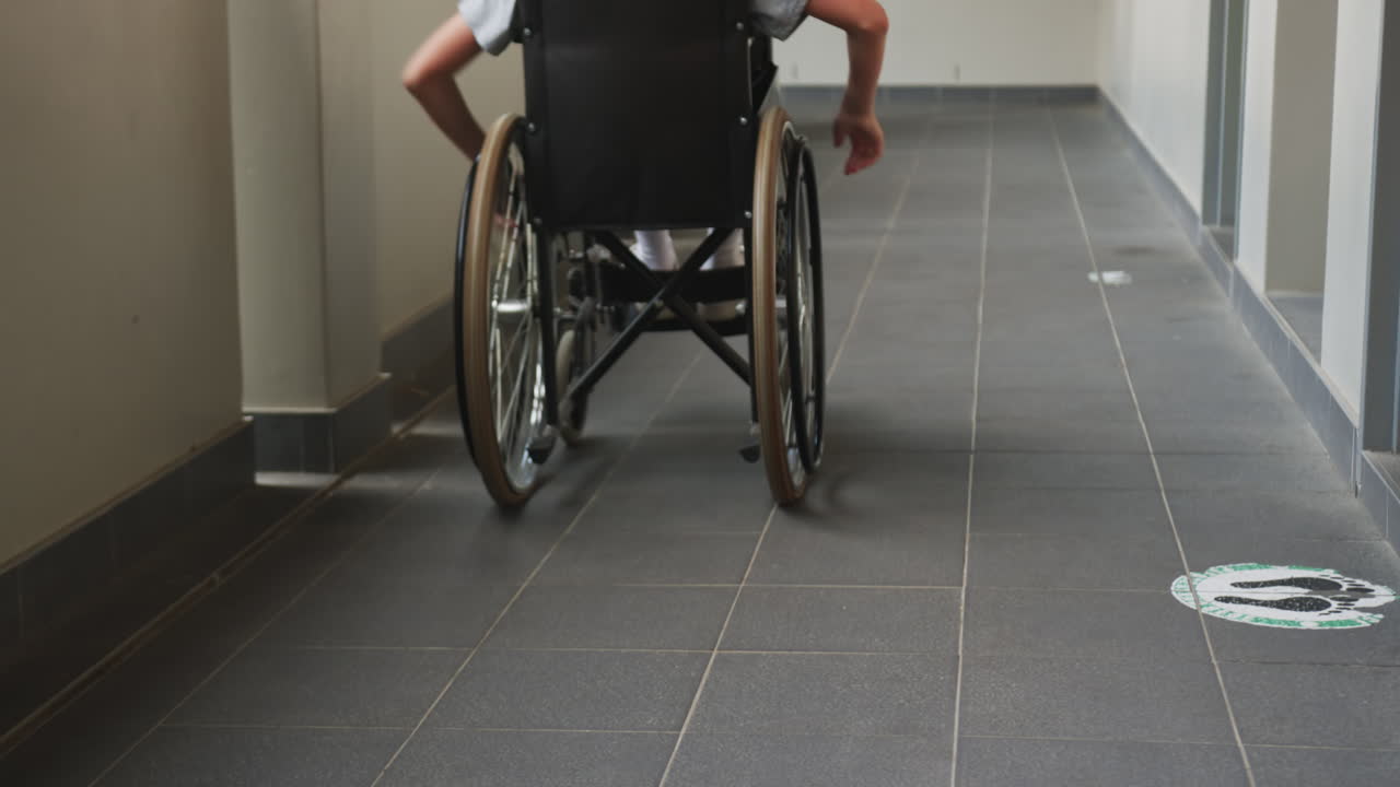 Navigating independently, student in wheelchair moving down school hallway