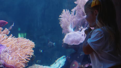 mother with little girl in aquarium looking at fish in tank excited child watching marine animals with curiosity having fun learning about sea life with mom in oceanarium