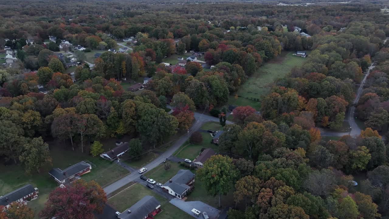 Un'auto percorre la strada di un tranquillo quartiere negli Stati Uniti. Alberi colorati in autunno. Ampia ripresa aerea. Giornata nuvolosa nello stato della Virginia, America. Zona residenziale periferica con case