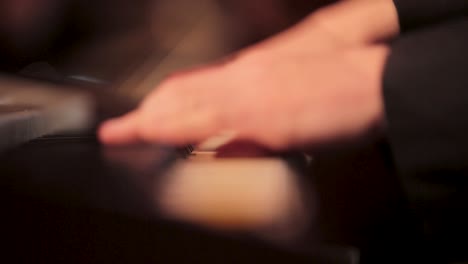 close-up of a hand playing piano keys in a dimly lit setting