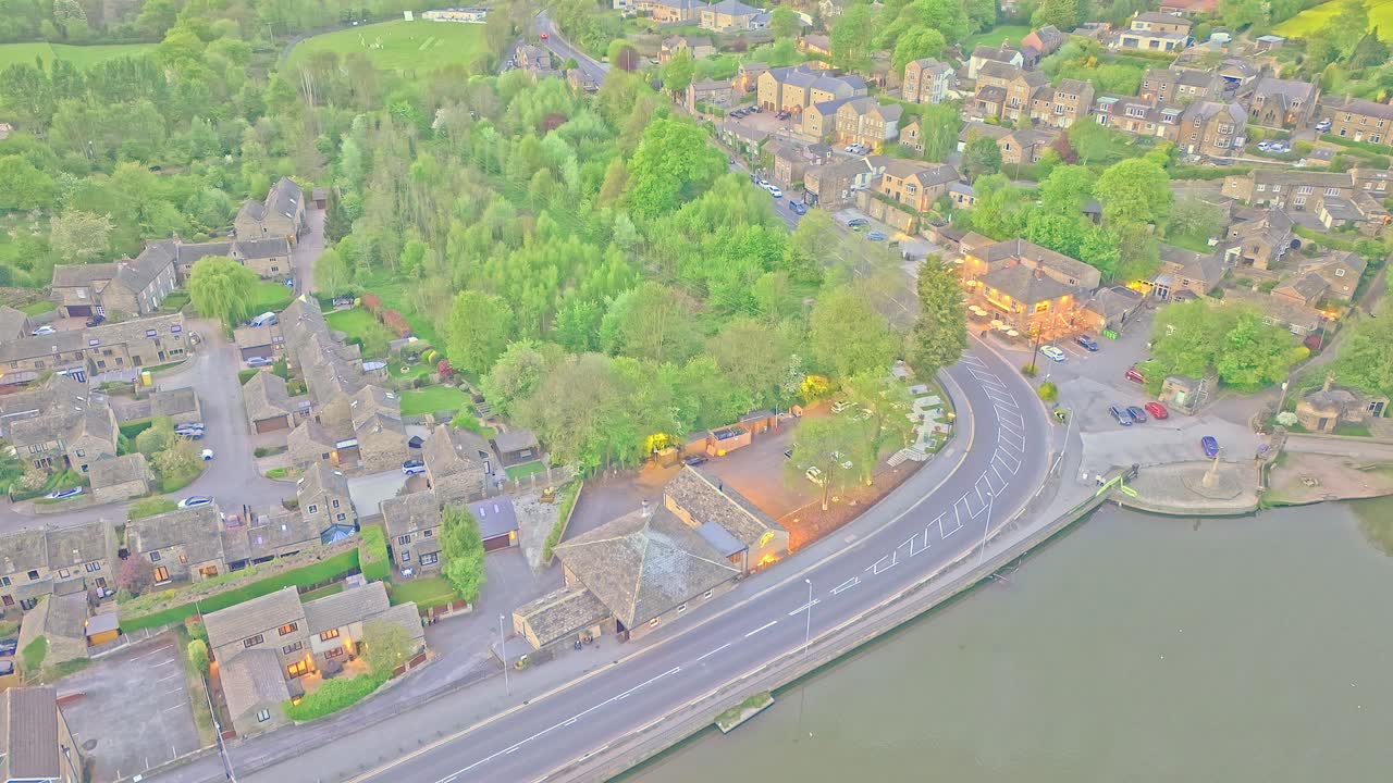 Aerial: road next to Newmillerdam Country Park lake during the day in Newmillerdam, suburb of Wakefield, West Yorkshire, England, crane down drone shot